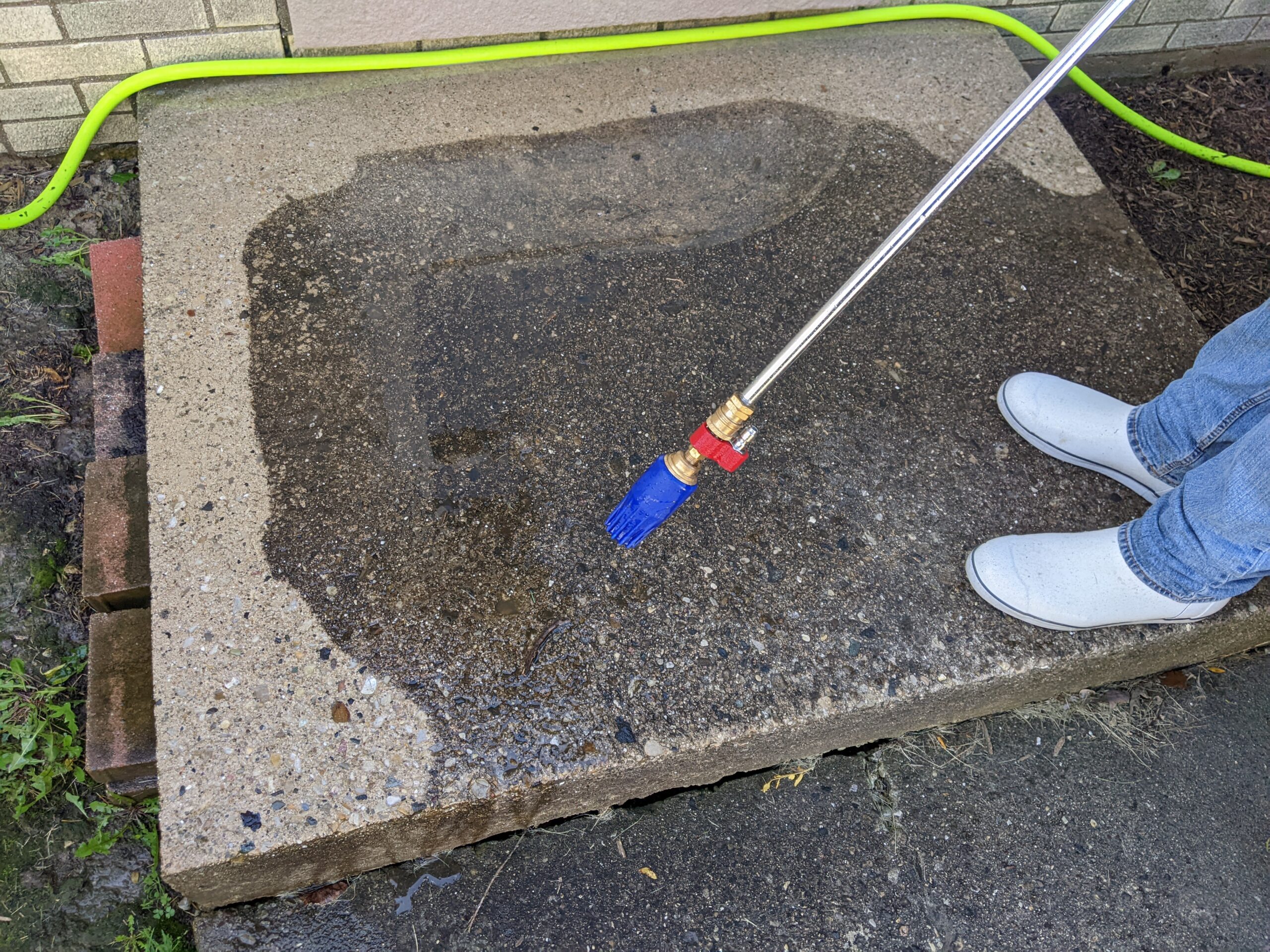 Showing concrete stoop being cleaned with a high pressure turbo nozzle.